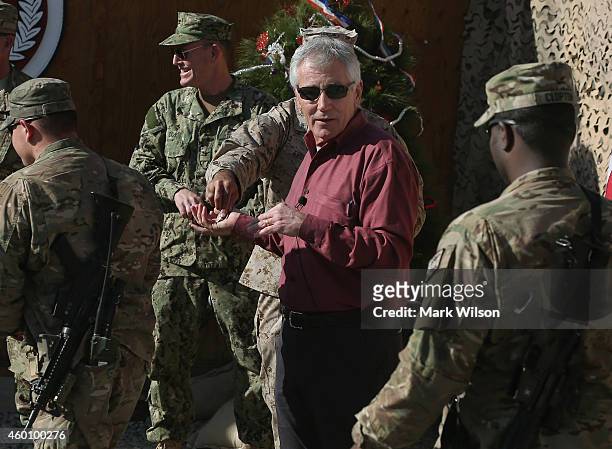 Secretary of Defense Chuck Hagel is handed a commemorative Sec. Def. Coin to give American troops during a visit, December 7, 2014 in FOB Gamberi,...