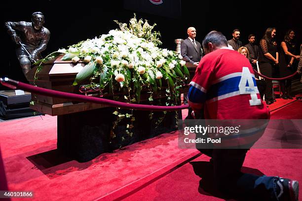 Fan kneels in front of the casket of former Montreal Canadiens player Jean Beliveau during the public viewing at the Bell Centre on December 7, 2014...