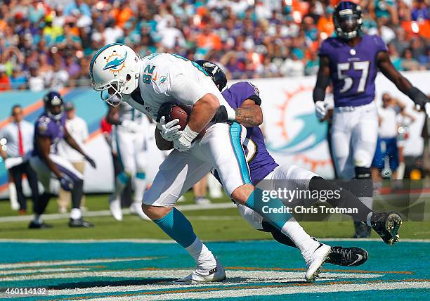 Wide receiver Brian Hartline of the Miami Dolphins catches a first quarter touchdown pass as cornerback Asa Jackson of the Baltimore Ravens defends...