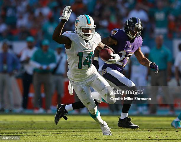 Wide receiver Jarvis Landry of the Miami Dolphins picks up second-half yardage as cornerback Asa Jackson of the Baltimore Ravens pursues during a...