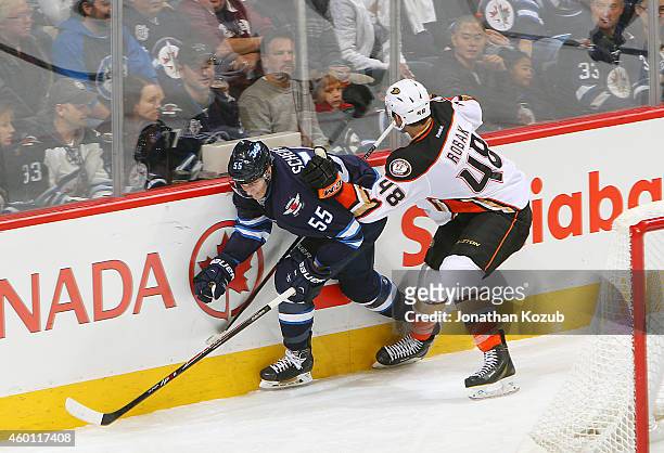 Mark Scheifele of the Winnipeg Jets slips past the check of Colby Robak of the Anaheim Ducks during third period action on December 7, 2014 at the...