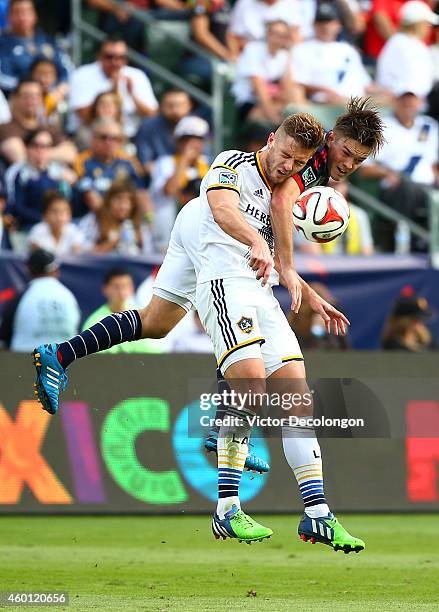 Robbie Rogers of the Los Angeles Galaxy takes an elbow to the jaw from Kelyn Rowe of the New England Revolution as they vie for the ball in the...