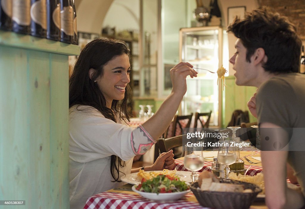 Happy young couple eating together in restaurant