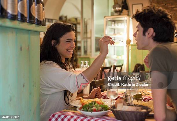 happy young couple eating together in restaurant - eating together stock pictures, royalty-free photos & images