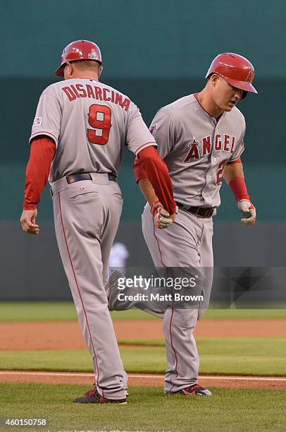 Mike Trout of the Los Angeles Angels high fives third base coach Gary DiSarcina after hitting a home run during game 3 of the American League...