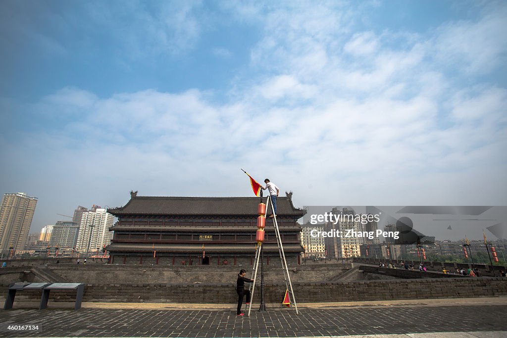 Workers are hanging red lantern on the city wall.  Xian City...