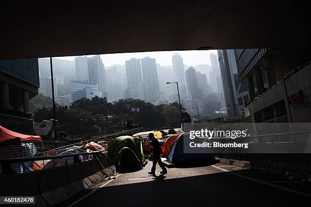 Man is silhouetted walking past tents on a flyover in the Admiralty district of Hong Kong, China, on Tuesday, Dec. 9, 2014. Pro-democracy...