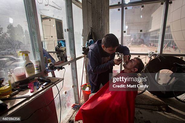 An Iraqi Christian, who fled from his home because of Islamic State's advance earlier this year, operates a barber shop inside the entrance hall of...