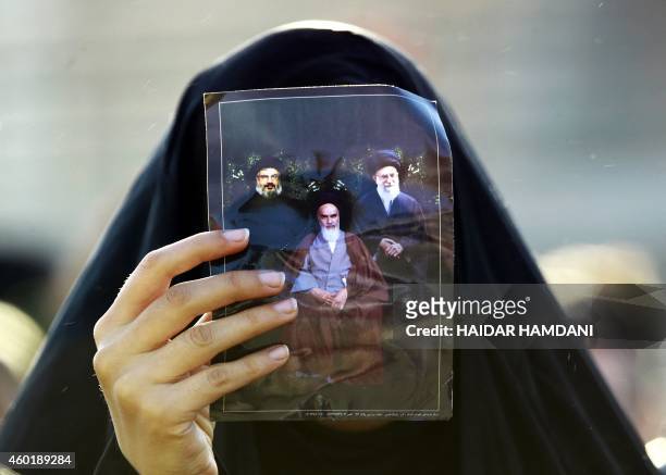Shiite Muslim pilgrim holds up a picture of Iranian supreme leader Ayatollah Ali Khamenei , Iran's late founder of the Islamic Republic Ayatollah...