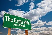 The Extra Mile Just Ahead Green Road Sign Over Sky