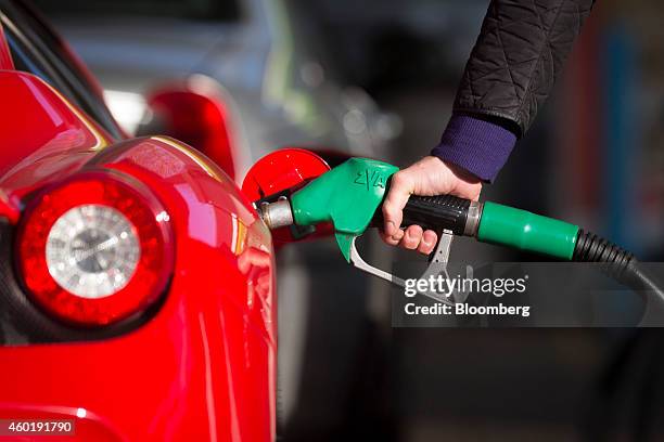 Driver refuels his luxury Ferrari automobile with unleaded petrol at an Esso gas station, operated by Exxon Mobil Corp., in Guildford, U.K., on...