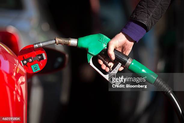 Driver holds a fuel nozzle as he prepares to refuel his luxury Ferrari automobile with unleaded petrol at an Esso gas station, operated by Exxon...