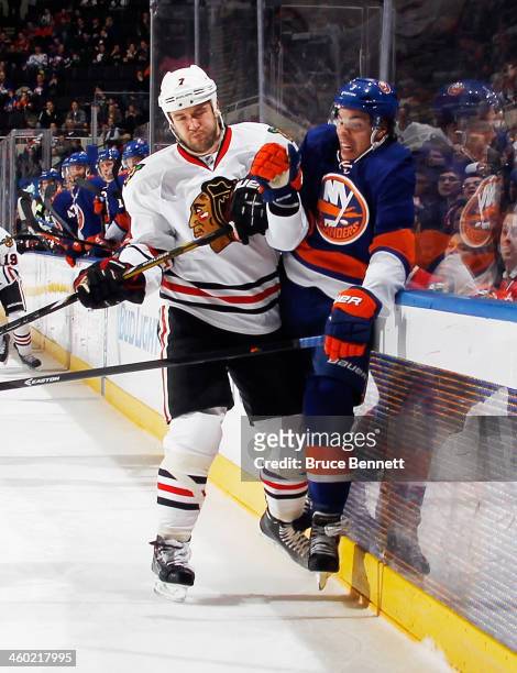 Travis Hamonic of the New York Islanders is hit into the boards by Brent Seabrook of the Chicago Blackhawks at the Nassau Veterans Memorial Coliseum...