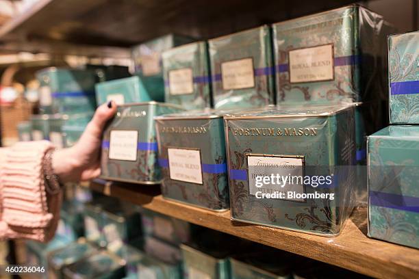 Shopper selects a tin of specialty tea displayed for sale inside a pop-up store, operated by Fortnum & Mason Plc, during a seasonal Christmas event...