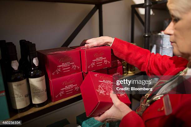An employee restocks Christmas puddings on a shelf inside a pop-up store, operated by Fortnum & Mason Plc, during a seasonal Christmas event at...