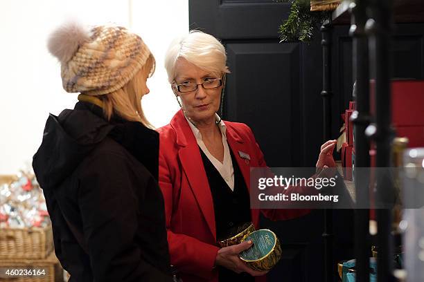 An employee, right, assists a customer inside a pop-up store, operated by Fortnum & Mason Plc, during a seasonal Christmas event at Somerset House in...