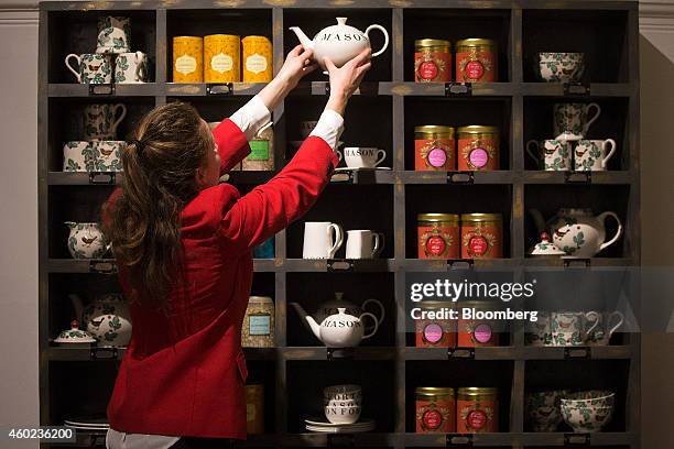 An employee places a teapot onto a specialty tea display shelf inside a pop-up store, operated by Fortnum & Mason Plc, during a seasonal Christmas...
