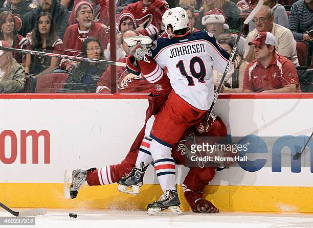 Antoine Vermette of the Phoenix Coyotes is checked into the boards by Ryan Johansen of the Columbus Blue Jackets during the second period at...
