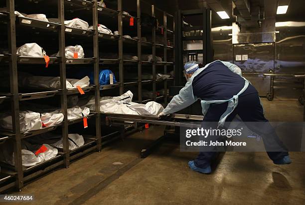 Forensic technician Kristine Clor handles human remains in the refrigerated morgue of the Pima County Office of the Medical Examiner on December 9,...