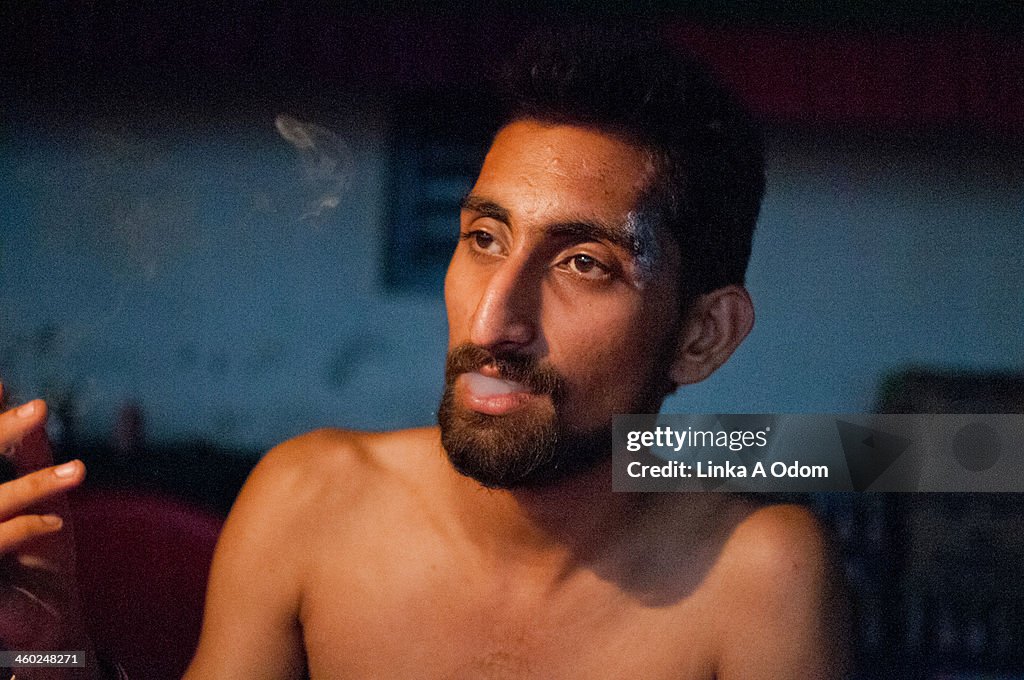 A young adult male from India smokes a cigarette.