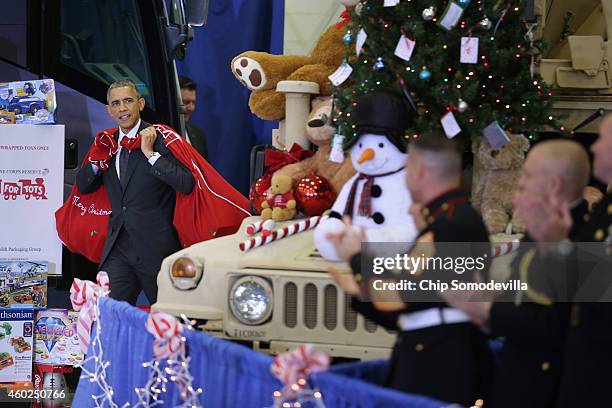 President Barack Obama, with bags slung over his shoulder, delivers toys and gifts donated by Executive Office of the President staff to the Marine...