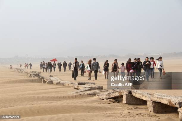 This picture taken on November 2, 2013 shows people walking beside an ancient stone bridge on the dried up lakebed of Poyang lake in Jiujiang, east...