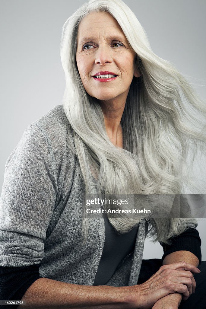 Mature woman with long, gray hair looking away.