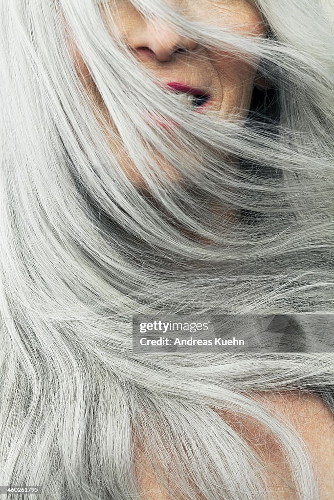 Mature woman with wind blown gray hair, cropped.