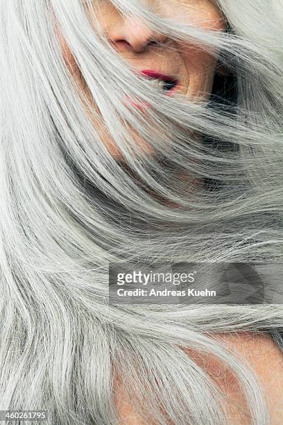 Mature woman with wind blown gray hair, cropped.