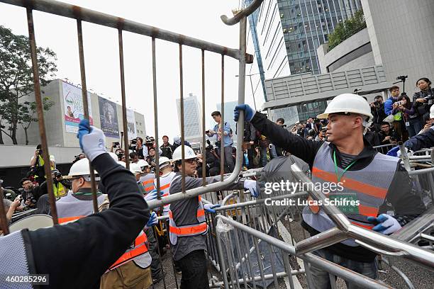 Workmen take down barricades put up by pro-democracy protesters under the supervision of bailiffs following a court injuction December 11, 2014 in...