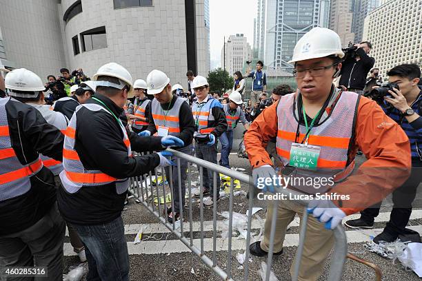 Workmen take down barricades put up by pro-democracy protesters under the supervision of bailiffs following a court injuction December 11, 2014 in...