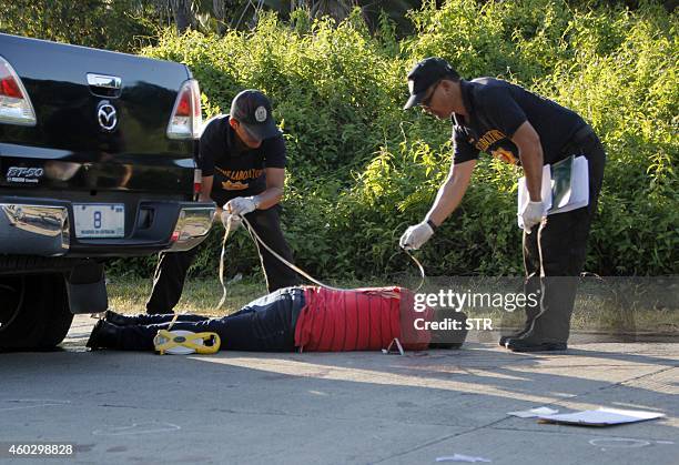 Police investigators look for evidence next to the body of a bodyguard for a Philippine legislator whose convoy was ambushed at the international...