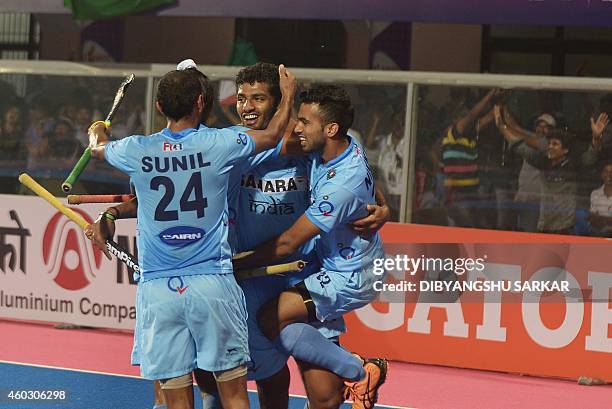 India's hockey player Sannuvanda Uthappa with teammates Chandanda Thimmaiah and Sunil Somwarpet celebrate after scoring a goal against Belgium during...