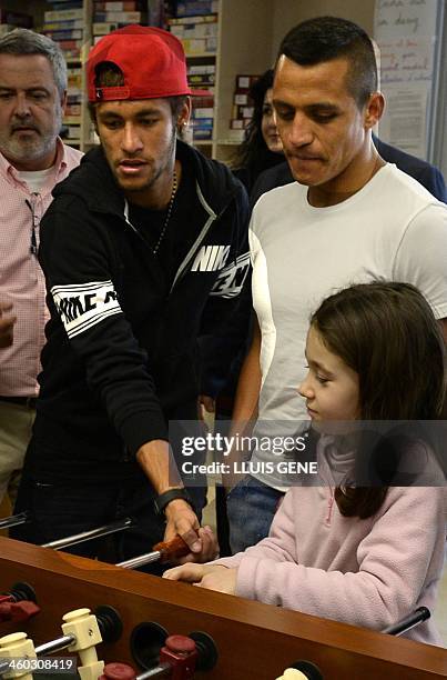 Barcelona's Brazilian forward Neymar da Silva Santos Junior and Barcelona's Chilean forward Alexis Sanchez play "futbolin" with children during a...