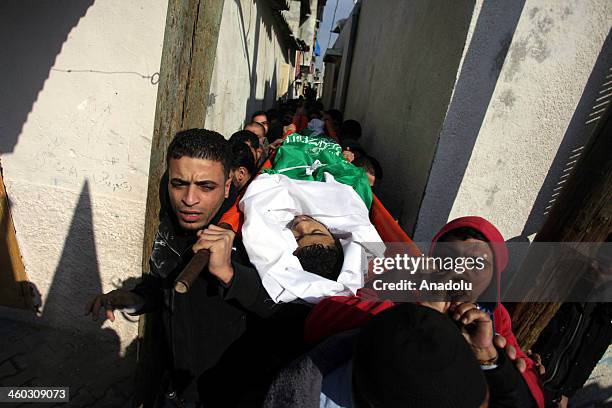 Palestinian mourners carry the body of Adnan Abu Khater during his funeral in Jabaliya refugee camp northern Gaza Strip on January 03, 2014. Abu...