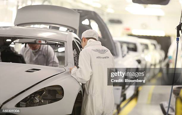 An employee checks paperwork associated with a primed Aston Martin Rapide S automobile in the paintshop at Aston Martin Lagonda Ltd.'s manufacturing...
