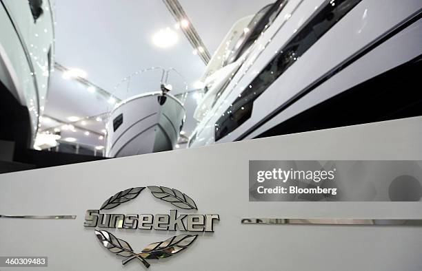 Logo sits near luxury yachts at the Sunseeker International Ltd. Display stand, a unit of China's Dalian Wanda Group, ahead of the 2014 London Boat...