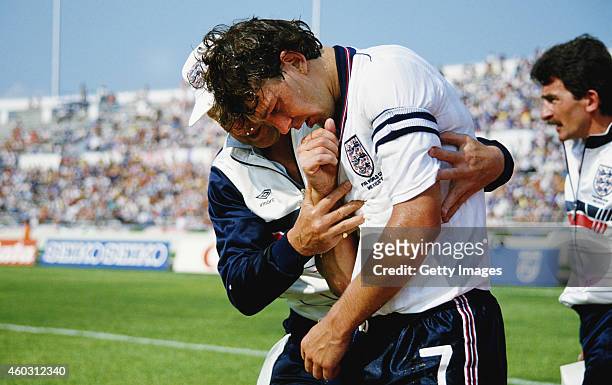 England player Bryan Robson and his injured right shoulder is helped off the pitch by physio Fred Street during the 1986 FIFA World Cup match between...