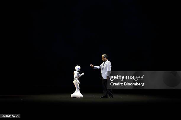 Bloomberg's Best Photos 2014: Billionaire Masayoshi Son, chairman and chief executive officer of SoftBank Corp., right, gestures towards a human-like...