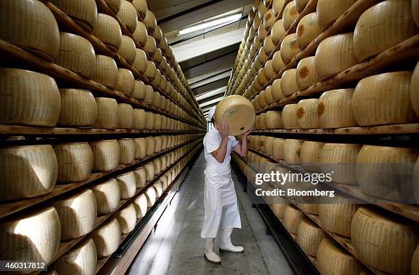 Bloomberg's Best Photos 2014: A worker selects a whole Parmigiano-Reggiano cheese from a storage rack ahead of inspection at Coduro cheesemakers in...