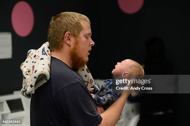 Justin Johnson holds his newborn baby, Jason, while his wife Mary starts a load of laundry in the laundry room at the Almost Home Hughes Station...