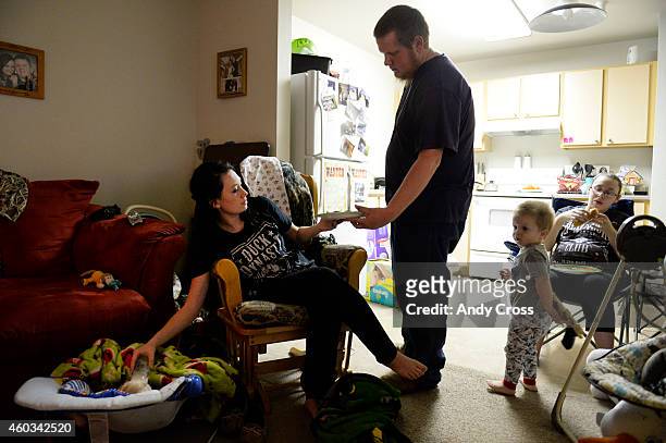 Justin Johnson, third from left, gives his wife, Mary, her dinner while Mary feeds their newborn baby, Jason at their apartment at Almost Home Hughes...