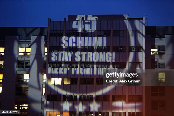 Fans project a message reading '45 - Schumi Stay strong! Keep fighting!' on a wall of the Grenoble University Hospital Centre where former German...