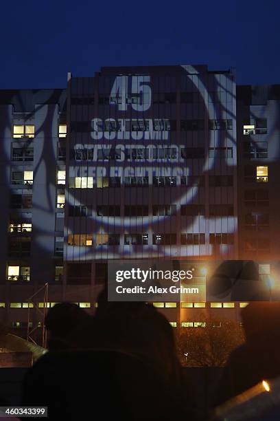 Fans project a message reading '45 - Schumi Stay strong! Keep fighting!' on a wall of the Grenoble University Hospital Centre where former German...