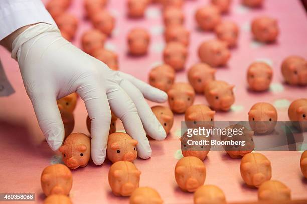 An employee holds a marzipan piglet during the hand-painting process inside the factory of traditional confectionary maker JG Niederegger GmbH in...