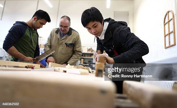 Refugees Luan from Vietnam and Jose Manuel from Portugal who arrived in Germany without family members train in wood-working techniques with training...