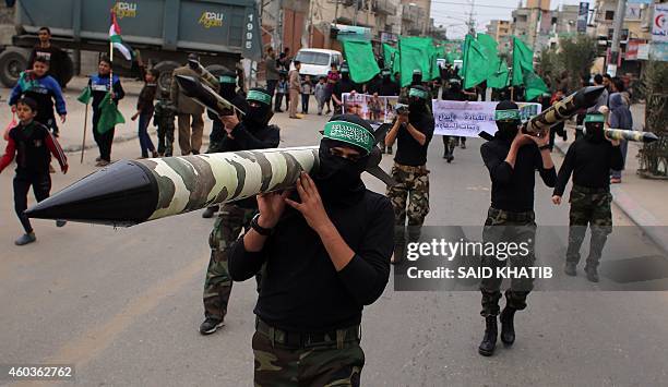 Palestinian militants from the Ezzedine al-Qassam brigade, the armed wing of Hamas, carry mock-rockets as they march during a rally to commemorate...