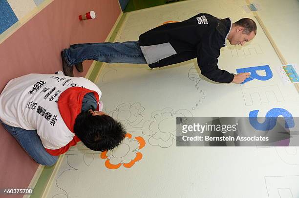 Employees paint a wall during an AEG Season Of Giving Event at South Park Elementary School on December 12, 2014 in Los Angeles, California.