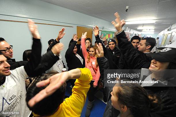 Employees participate in an exercise during an AEG Season Of Giving Event at South Park Elementary School on December 12, 2014 in Los Angeles,...