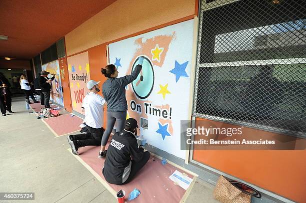 Employees paint an outside wall during an AEG Season Of Giving Event at South Park Elementary School on December 12, 2014 in Los Angeles, California.